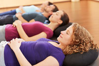 Mehrere Frauen und Männer liegen entspannt mit geschlossenen Augen auf einer Gymnastikmatte.